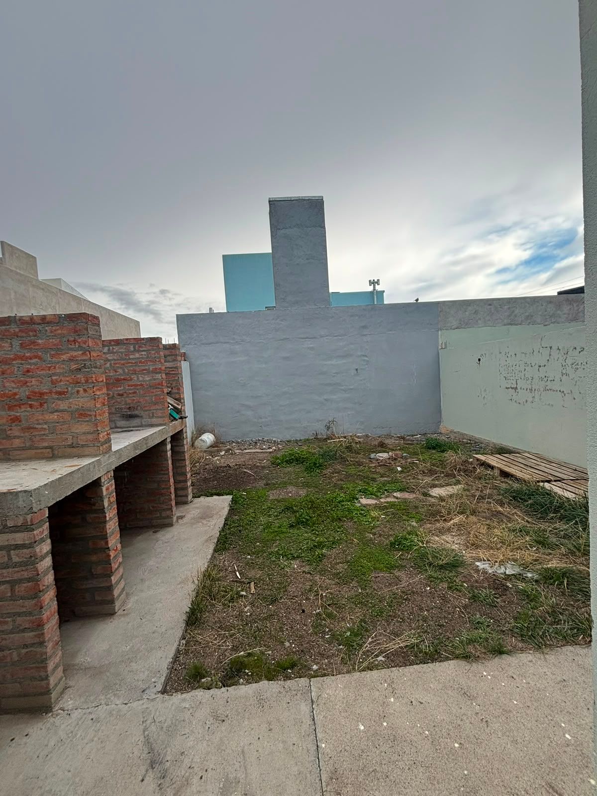 Patio con parrilla de ladrillo y espacio de tierra y pasto